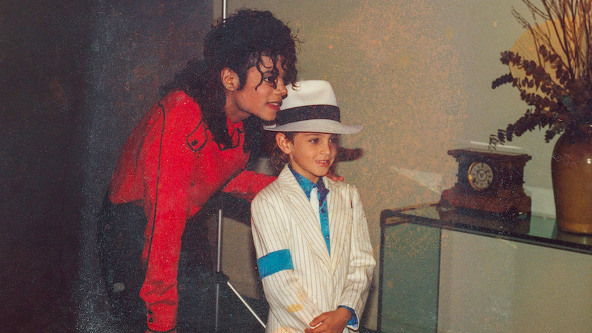 Michael Jackson whispers to a young boy dressed in a costume