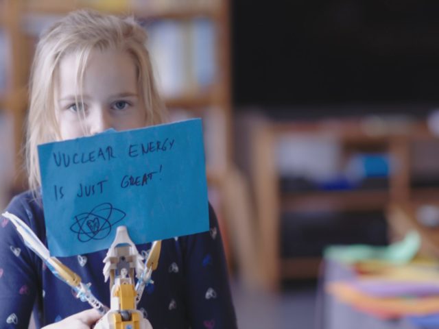A girl holds a sign that reads 'Atomic energy is just great'