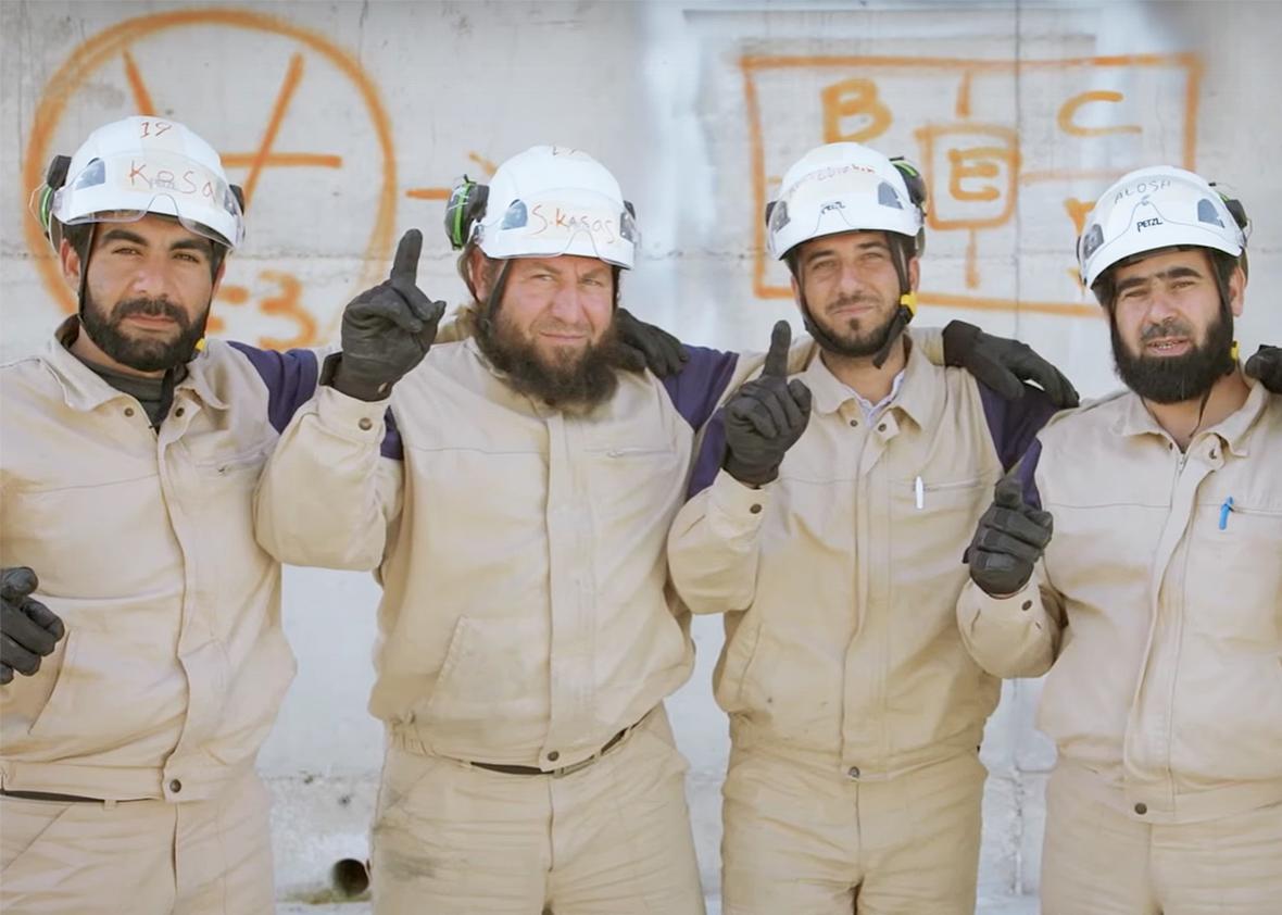 Four men in white helmets look at the camera smiling